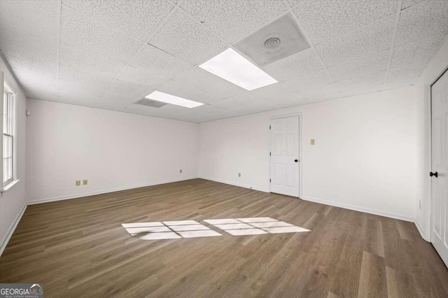 unfurnished room with wood-type flooring and a drop ceiling