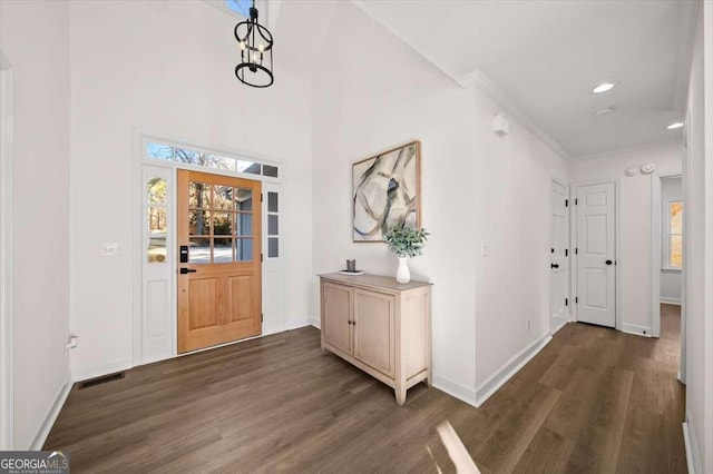 foyer entrance with dark hardwood / wood-style flooring, an inviting chandelier, and ornamental molding