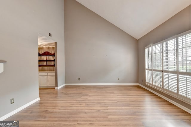 spare room with light wood-type flooring and vaulted ceiling