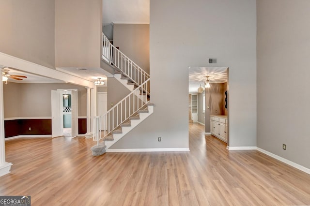 interior space with a high ceiling, ceiling fan, and light hardwood / wood-style flooring