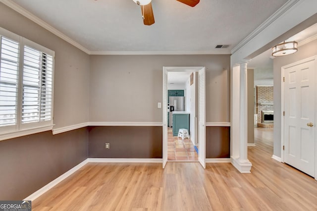 spare room with ornamental molding, ceiling fan, light hardwood / wood-style flooring, and a brick fireplace