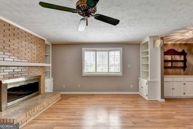 unfurnished living room with a fireplace, a textured ceiling, ceiling fan, and light hardwood / wood-style flooring