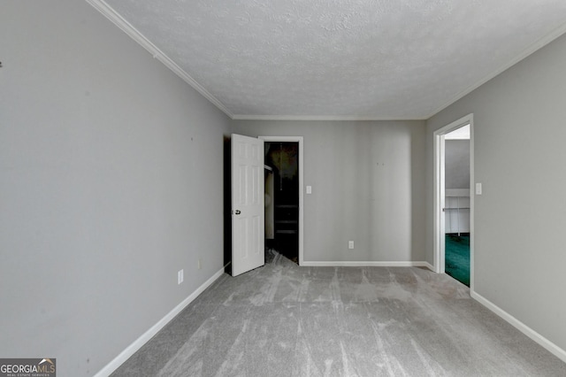 spare room with a textured ceiling, ornamental molding, and light carpet