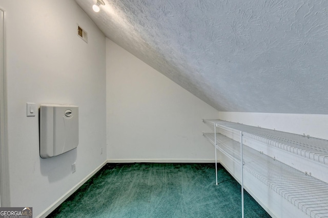 interior space featuring lofted ceiling, dark carpet, and a textured ceiling