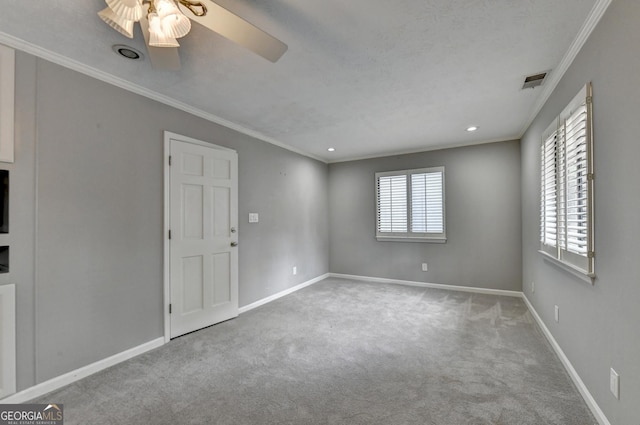 spare room with ceiling fan, crown molding, and light carpet