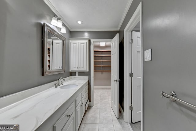 bathroom with a textured ceiling, ornamental molding, tile patterned floors, and vanity