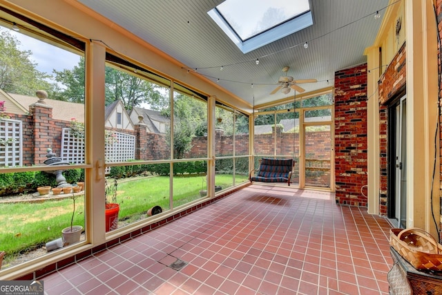 unfurnished sunroom featuring a wealth of natural light, ceiling fan, and vaulted ceiling with skylight