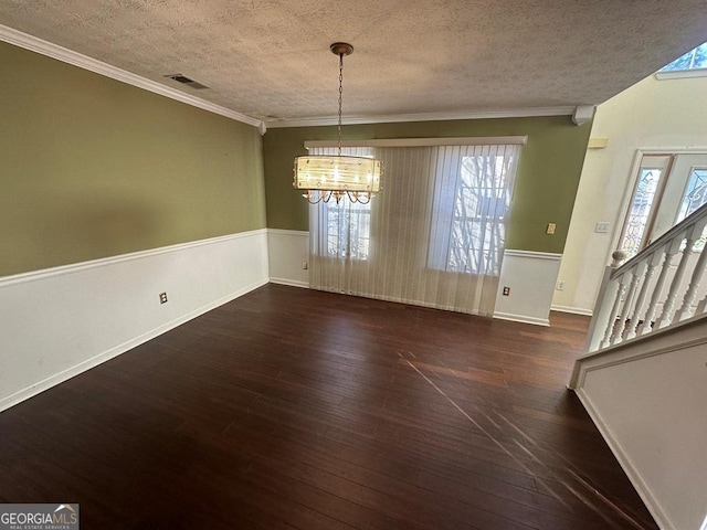 unfurnished dining area with an inviting chandelier, ornamental molding, a textured ceiling, and dark hardwood / wood-style floors