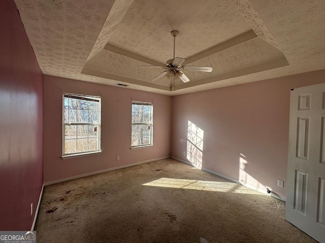 spare room with a raised ceiling, ceiling fan, a textured ceiling, and light carpet