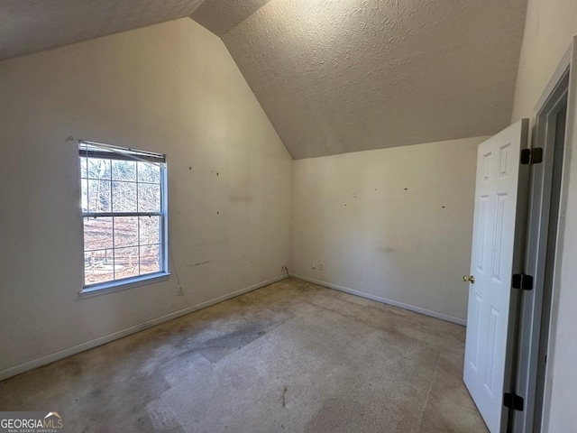 additional living space featuring a textured ceiling and vaulted ceiling