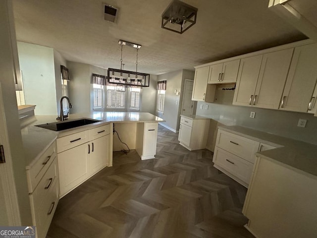 kitchen with sink, a center island, white cabinetry, and hanging light fixtures