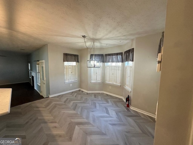 unfurnished dining area featuring dark parquet flooring and a textured ceiling