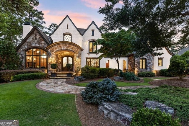 view of front of house with french doors and a lawn