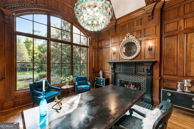 home office featuring a healthy amount of sunlight, wood walls, and a chandelier