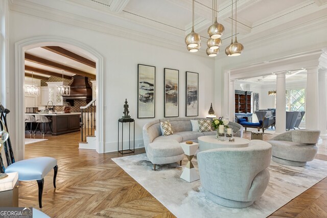 living room with light parquet flooring, beam ceiling, an inviting chandelier, decorative columns, and sink