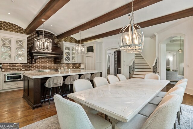 dining room with lofted ceiling, wood-type flooring, sink, and brick ceiling