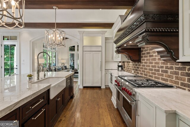 kitchen with range with two ovens, hanging light fixtures, decorative backsplash, dark brown cabinetry, and sink