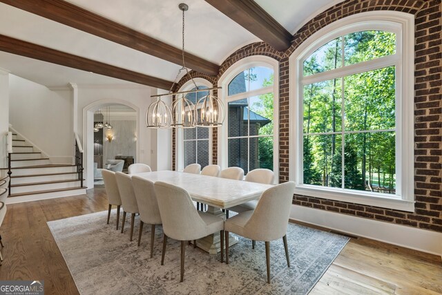 dining space with beamed ceiling, light hardwood / wood-style flooring, and a chandelier