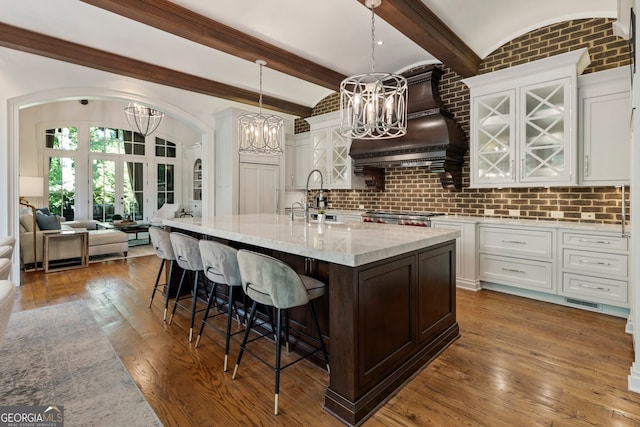 4874 Kettle River Pt, Suwanee, GA 30024 - kitchen with a sink, an inviting chandelier, white cabinetry, light stone counters, and a breakfast bar area