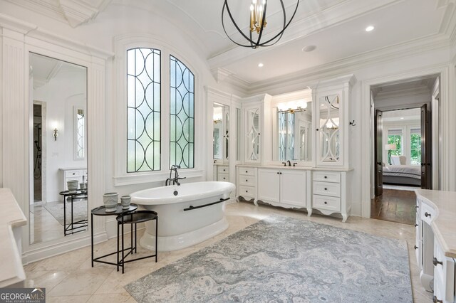 bathroom featuring ornamental molding, vanity, a tub to relax in, and a notable chandelier