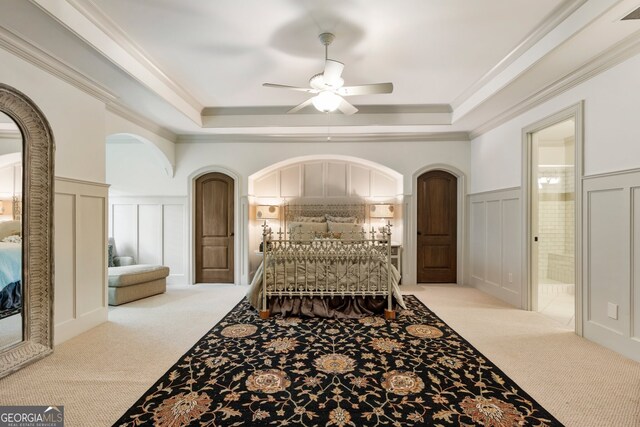 bedroom with a raised ceiling, light colored carpet, and ceiling fan