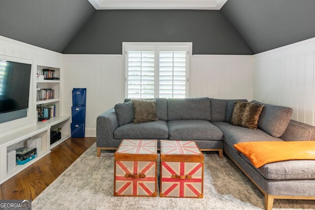 living room with lofted ceiling, wood-type flooring, ornamental molding, and built in features