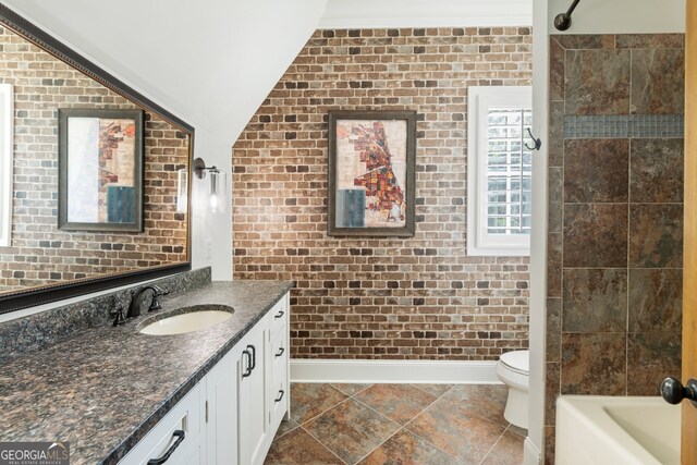 full bathroom with toilet, brick wall, lofted ceiling, shower / tub combination, and vanity