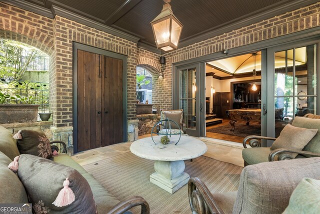 living room featuring pool table, brick wall, crown molding, and plenty of natural light