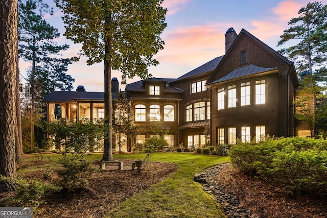 back house at dusk featuring a yard