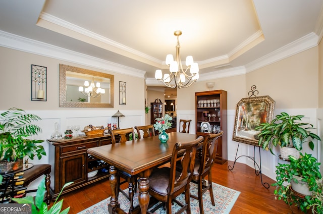 dining area featuring a notable chandelier, crown molding, dark hardwood / wood-style floors, and a tray ceiling