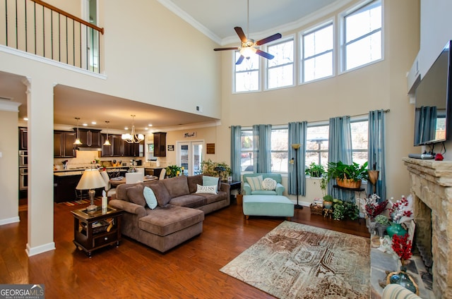 living room with ceiling fan with notable chandelier, a high ceiling, ornamental molding, and dark hardwood / wood-style floors