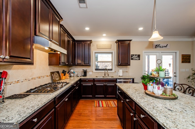 kitchen with sink, stainless steel appliances, light hardwood / wood-style flooring, light stone countertops, and pendant lighting