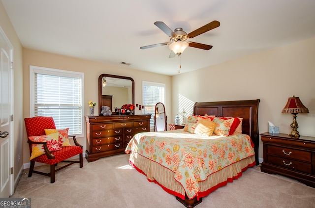 bedroom featuring multiple windows, light carpet, and ceiling fan