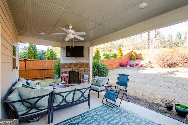 view of patio / terrace with ceiling fan and an outdoor living space with a fireplace