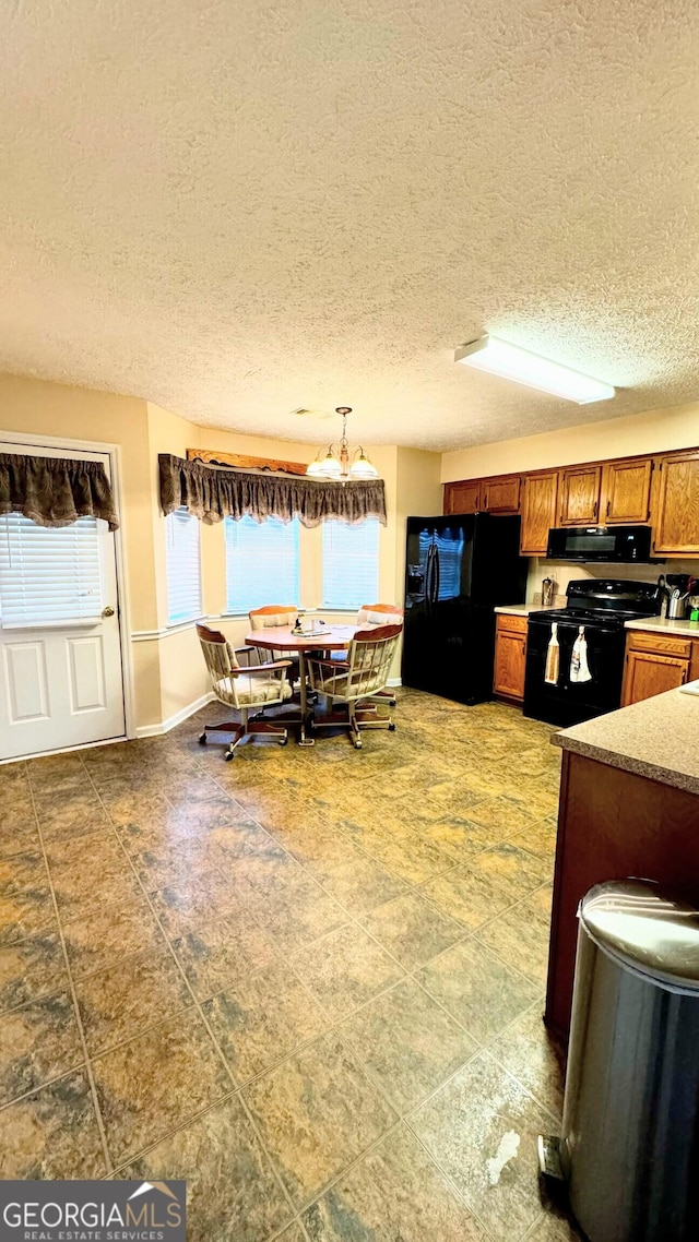 kitchen featuring hanging light fixtures, a textured ceiling, and black appliances