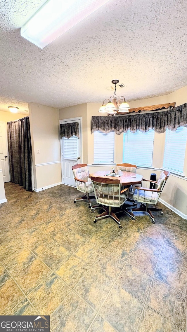 dining area with an inviting chandelier, a wealth of natural light, and a textured ceiling