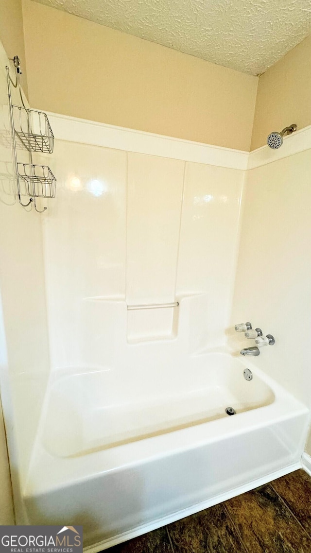 bathroom featuring shower / washtub combination and a textured ceiling