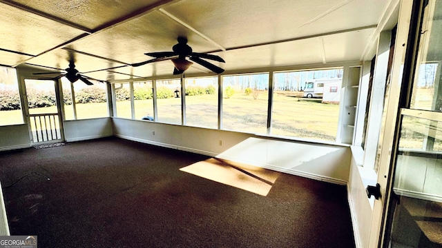 unfurnished sunroom featuring ceiling fan and a wealth of natural light