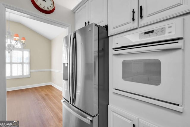 kitchen featuring lofted ceiling, light wood-type flooring, white oven, stainless steel refrigerator with ice dispenser, and a chandelier