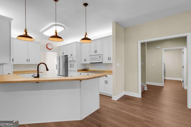 kitchen with white appliances, white cabinetry, pendant lighting, and kitchen peninsula