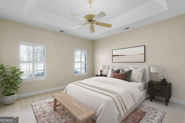 carpeted bedroom with a raised ceiling and ceiling fan