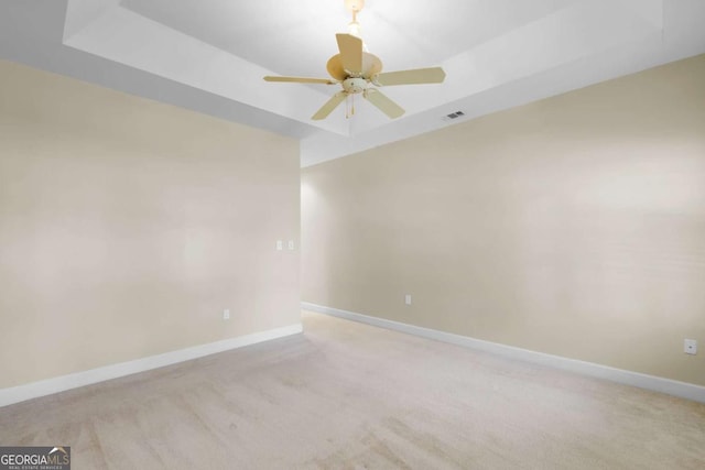 carpeted empty room featuring ceiling fan and a tray ceiling