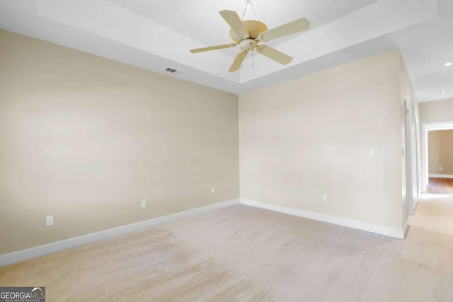 spare room featuring light carpet and a tray ceiling