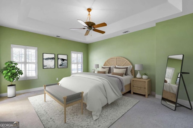 carpeted bedroom featuring ceiling fan and a raised ceiling