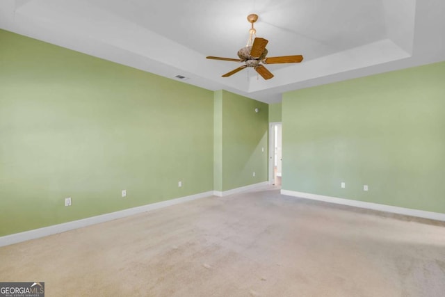 empty room featuring ceiling fan, a tray ceiling, and carpet