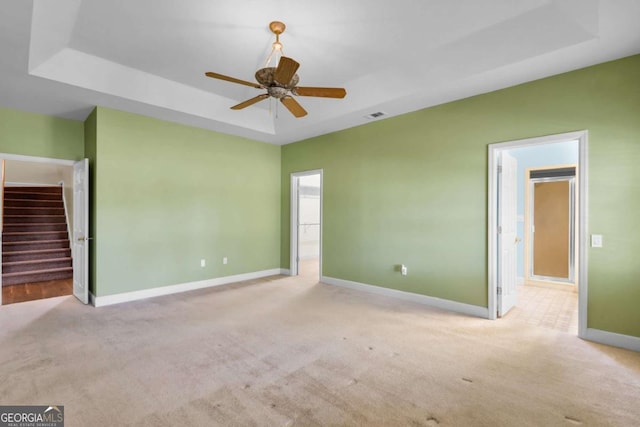 carpeted spare room featuring ceiling fan and a tray ceiling