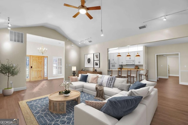 living room with vaulted ceiling, ceiling fan with notable chandelier, and hardwood / wood-style flooring