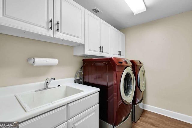 laundry area featuring sink, cabinets, hardwood / wood-style floors, and independent washer and dryer