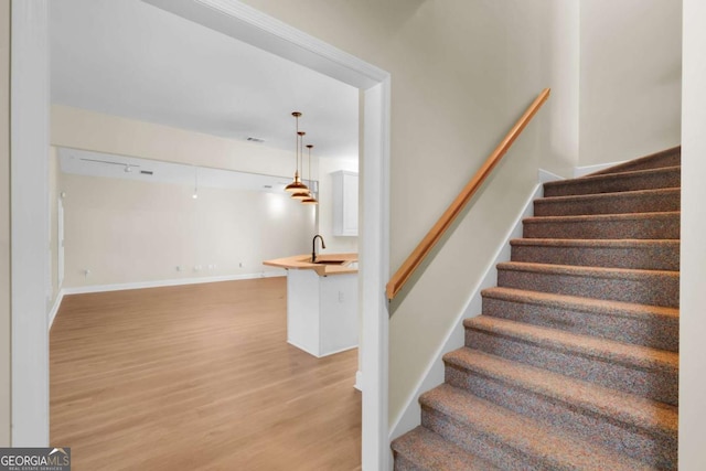 stairs featuring sink and hardwood / wood-style flooring