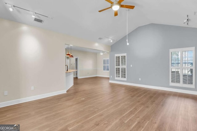 unfurnished living room featuring lofted ceiling, track lighting, ceiling fan, and light hardwood / wood-style flooring